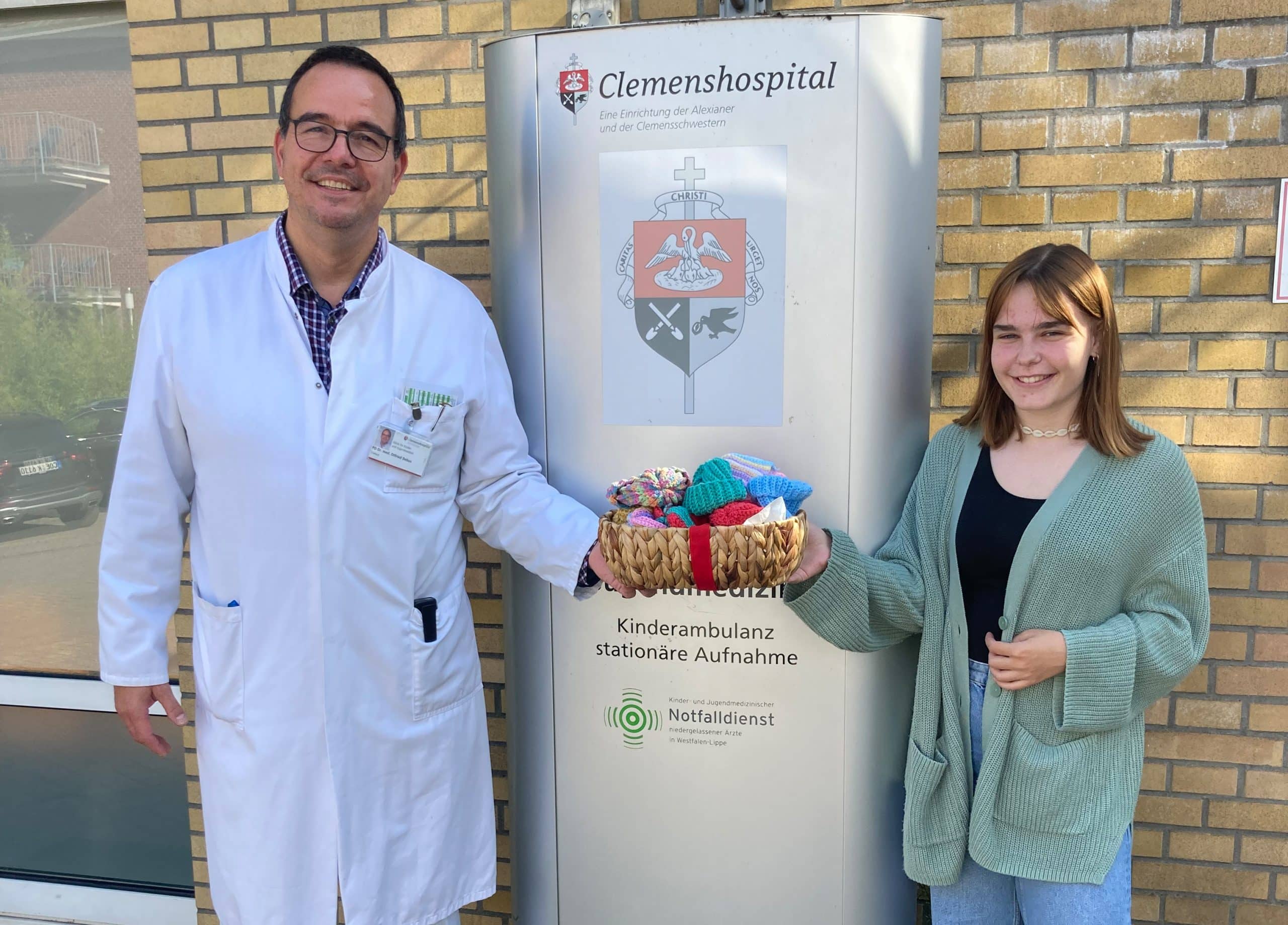 Chefarzt Dr. Otfried Debus (l.) und Emma Schulz mit einem Körbchen voller bunter Häkelmützchen.