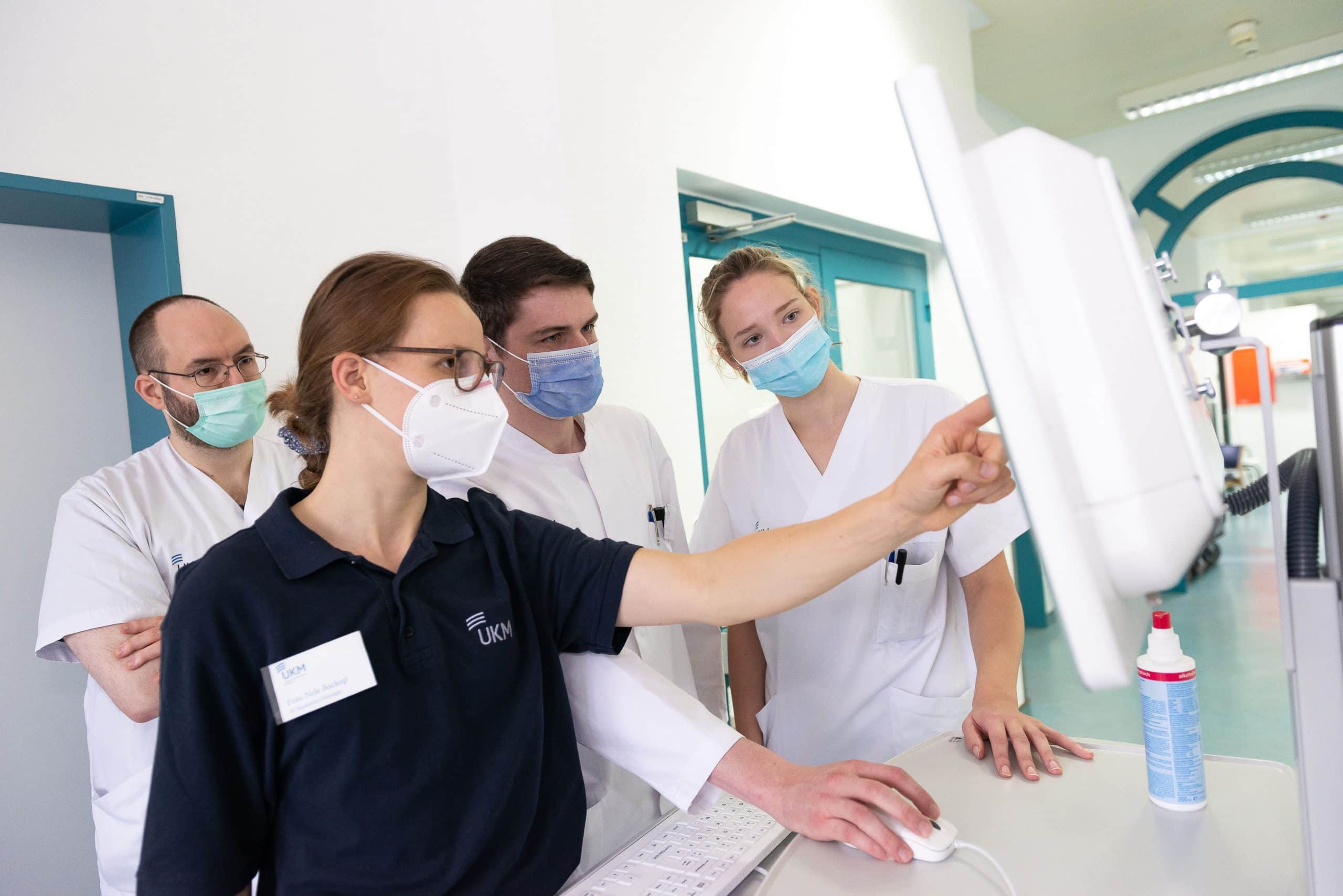Nele Buckup (vorne) bespricht gemeinsam mit Luisa Konert (rechts) einen gemeinsamen Patientenfall. Die angehende Ärztin und angehende Pflegekraft haben in den vergangenen vier Wochen zusammen im interprofessionellen Unterrichtskonzept Patienten versorgt. Im Hintergrund unterstützen dabei sogenannte Lernbegleitende. (© Foto UKM/Jeremies)