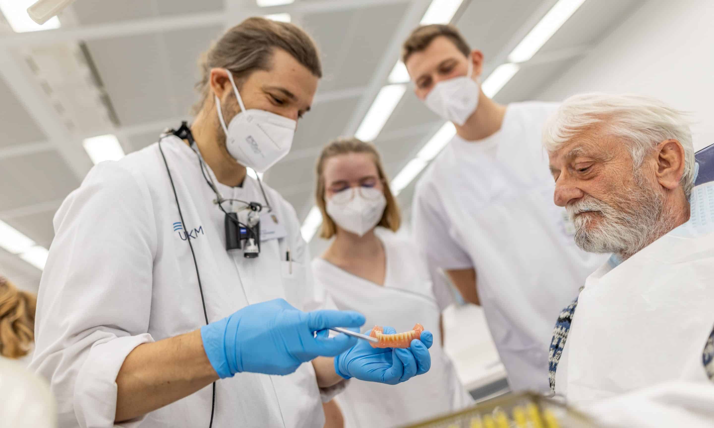 Der betreuende Zahnarzt Dr. Nico Peter Schwarzbach gibt den Studierenden Amelie Zipser und Nick Paßlack sowie dem „Klinik-Profi“ Dieter Eich Tipps für das Einsetzen der neuen „Dritten“ (Foto: WWU / P. Leßmann)